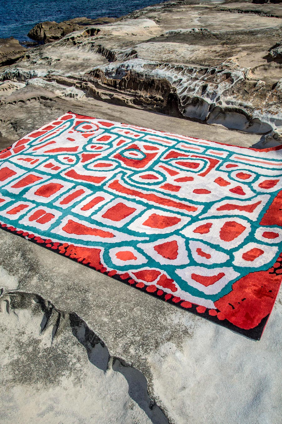 Indigenous Lungarung rug in red and green colour in a coastal setting