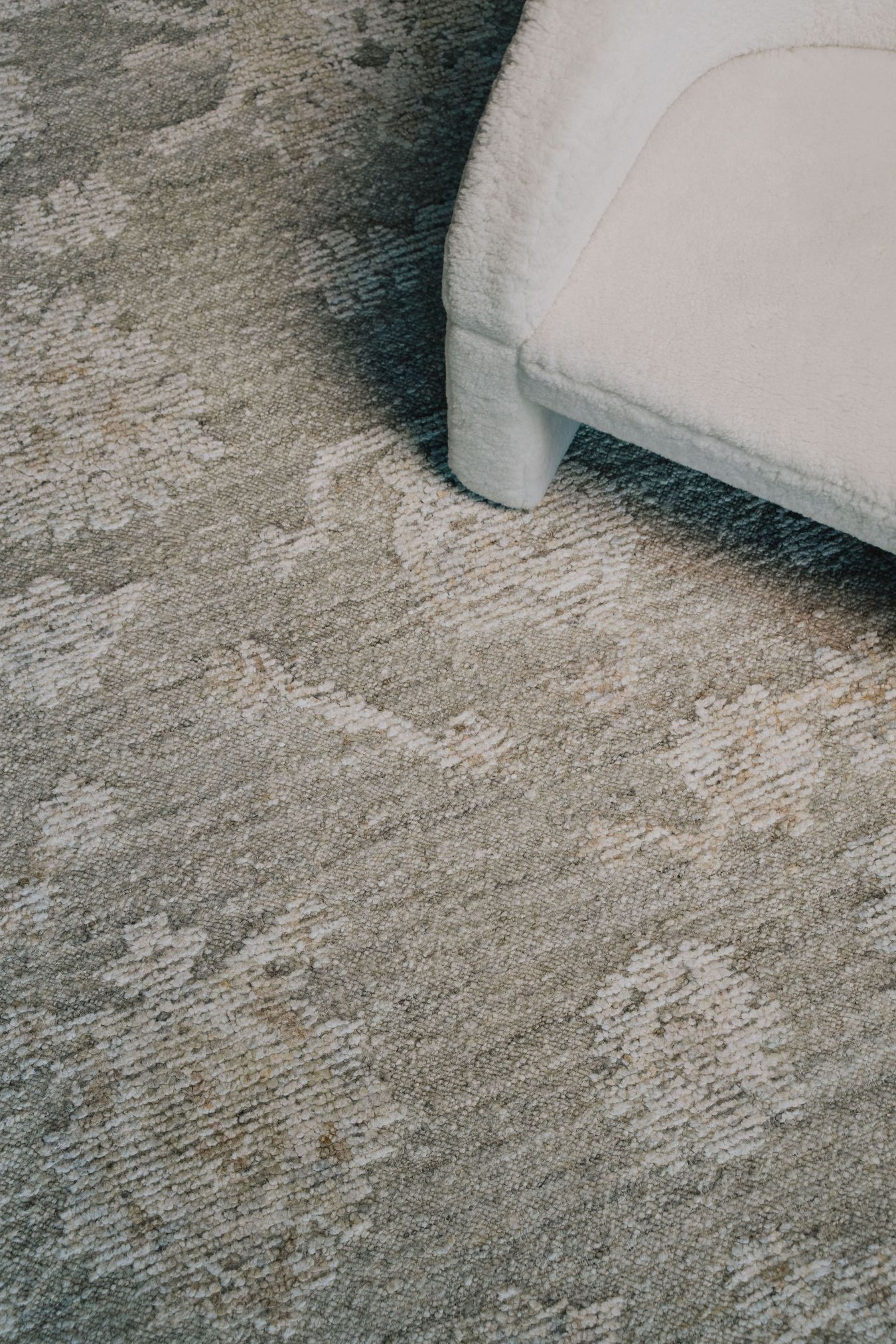 location image of the Olan rug from the Oushak Collection, featuring a textured grey, taupe and cream pattern beneath a white
