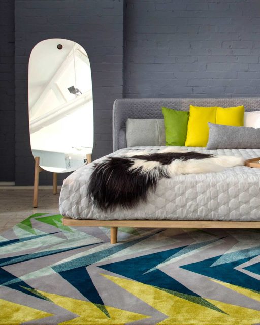 Bedroom view of our gemoetrically patterned Anika rug in navy, yellow and blue